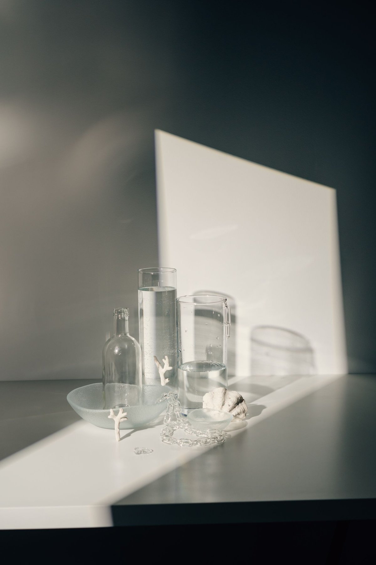 Transparent glass vessels and their shadows on a pale surface.