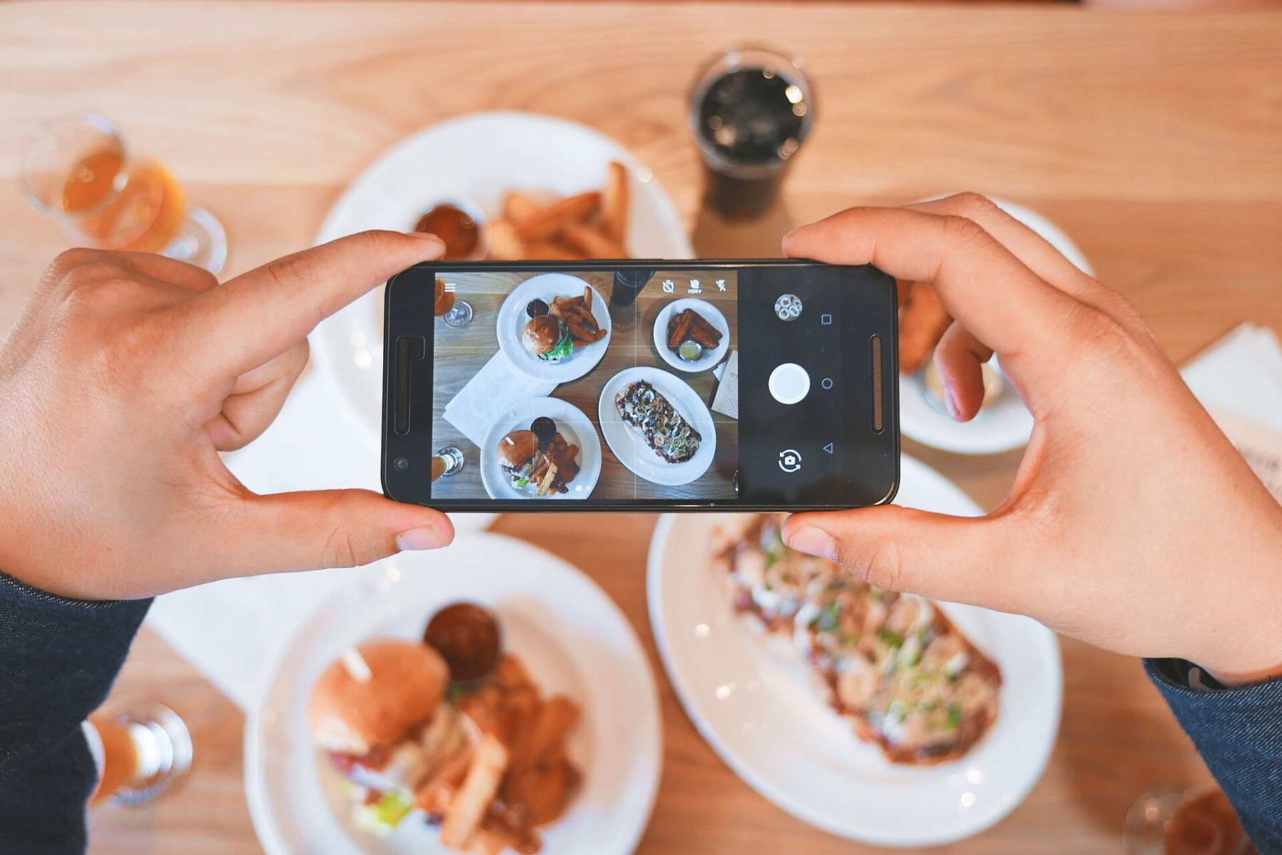 A person photographing food with a smartphone.