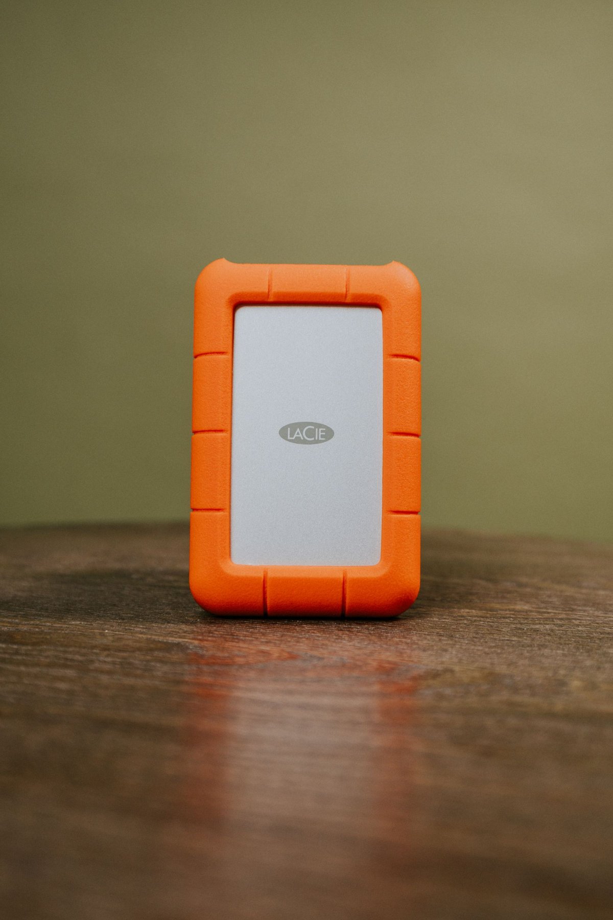 An external hard drive with an orange protective case.